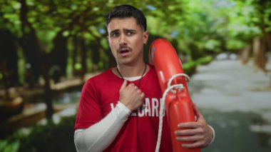 Sunny Park 'ta şamandıra tutan kırmızı tişörtlü genç İspanyol cankurtaran endişeli görünüyor..