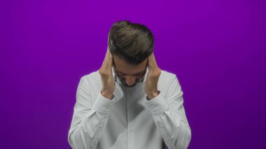 Beyaz gömlek giyen genç adam stüdyoda gözleri mor arkaplan ile kaplıyor; stres.