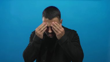 Genç İspanyol adam sıkıca burnunu sıkar ve canlı mavi stüdyoda gözlerini kapatır; koku rahatsız edici tiksinti.