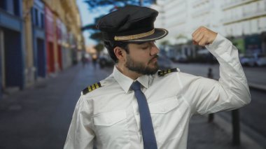 Sakallı, pilot üniforması ve şapkası olan genç bir adam şehrin bulanık arka planına karşı güç ve kararlılık hissini yakalıyor..