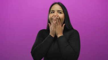 İzole edilmiş pembe bir arka plan karşısında coşkuyla gülen genç Latin kadın neşeli bir ifade ve canlı bir kişilik sergiliyor..