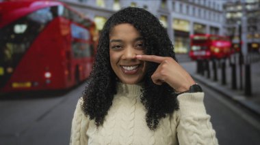 Kırmızı otobüslü kentsel trafiğin ortasında şehir caddesinde yanak yanağa gezen kadın; sevinç güveni iyimserliği.