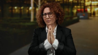 Kıvırcık saçlı ve gözlüklü bir kadın geceleri şehir sokaklarında el ele tutuşarak umudunu ve samimiyetini ifade ediyor..