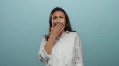 İzole edilmiş mavi arka planda beyaz gömlekli bir kadın gülüyor. Duygusal mizah ve neşe ifade ediyor.