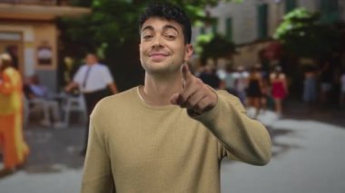 Adam arka planda el ele tutuşuyor. Genç İspanyol adam renkli arka planda gülümseme ve jest sergiliyor..