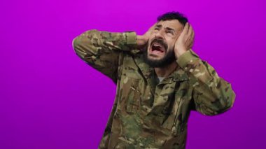Askeri üniformalı İspanyol bir adam canlı pembe arka plana karşı sıkıntı içinde. Duygularını ve yoğunluğunu aktarıyor..