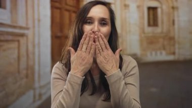 Eski bir kasaba sokağında gülümseyen ve üfleyen bir kadın, mutluluk ve samimiyet sergiliyor, büyüleyici, tarihi bir arka plana kurulmuş..