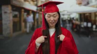 Kırmızı mezuniyet elbisesi ve şapkası olan kadın şehir sokaklarında bulanık bir şehir geçmişiyle kendini gösteriyor..