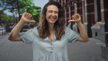 Renkli şehir caddesinde yapraklı ağaçların ve tuğla cephelerin altında gülümseyen genç İspanyol kadın..