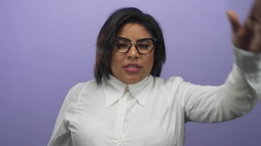 Beyaz gömlek ve gözlüklü, mor arka plan karşısında eli alnında hayal kırıklığını ifade eden bir kadın..