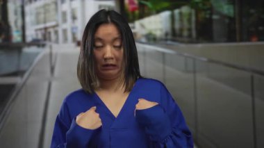 Şehir caddesinde şaşkın bir ifadeye sahip mavi bluzlu bir kadın gün ışığında açık hava ortamında kendini gösteriyor.