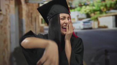 Mezuniyet kıyafetli bir kadın dışarıda gülüyor köy ortamında neşeli bir anı yakalıyor, başarıyı ve mutluluğu simgeliyor..