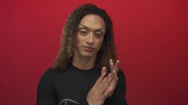 Avuç içlerini birbirine bastıran kadın stüdyoda kameraya bakacak şekilde hafif ışıklandırma altında kırmızı arkaplan; yansıma sükuneti tefekkür düşüncesi.