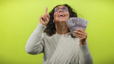 Endonezya banknotları tutan kadın gülümsüyor ve parlak sarı izole bir arka plana işaret ediyor başarı ve zenginliği temsil ediyor..