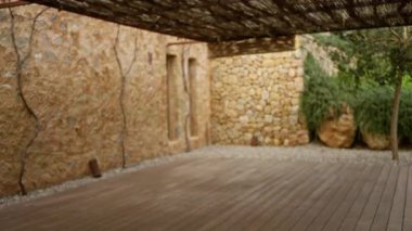 Kırsal taştan duvarları ve ahşap döşemeleri olan, yoga ve gevşeme için ideal, sakin bir ortam için yeşillik çerçeveli bir teras..