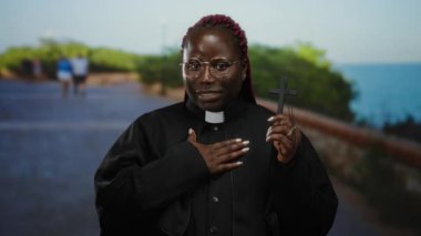 Rahip kılığındaki kadın deniz kenarındaki güvertede karşıdan karşıya geçiyor. Huzurlu sahil düzenine karşı ruhaniliği ve huzuru çağrıştırıyor..