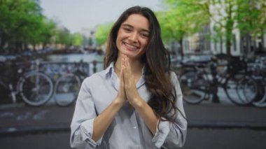 Latin kökenli genç bir kadın güneşli bir caddede parmaklarını çapraz gösteriyor. İyimserlik..