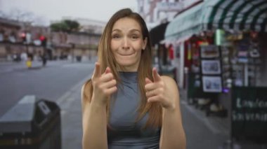 Kafkasyalı genç bir kadın canlı şehir caddesinde iki parmağını doğrudan kameraya doğrultuyor..