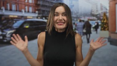 Sokakta araçlar ve tuğla binalarla kaplı bulanık yayaların arasında ağzı açık, siyah kolsuz bir kadın..