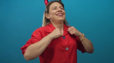 Kırmızı gömlekli, kolları açık, sarı saçlı ve kafası stüdyoda yana yatmış bir kadın..