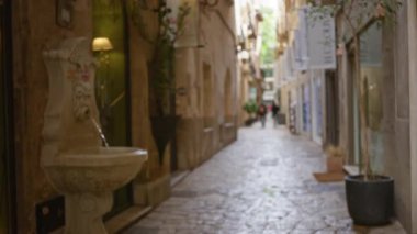 Eski çağlardan kalma bir çeşme ve sıcacık tonlarla bulanık bir Akdeniz caddesi manzarası eski kasabanın çekiciliğini ve yalnızlığını yansıtıyor..