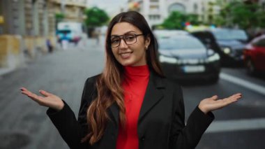 Kalabalık bir sokakta, güneşli bir günde, açık havada, geniş avuçlarıyla gülümseyen bir kadın kendine güvenen ve pozitif bir tavır sergiliyor..