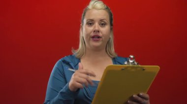 Kadın, notları okurken ve stüdyoda el ele hareket ederken pano ve kalem tutuyor; konsantrasyon analizi.