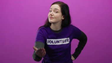 Kadın, canlı pembe bir arka planda gönüllü gömleği giyip arayarak bir jest yapıyor..