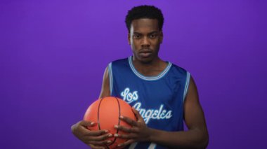 Merkezli adam basketbolu iki eliyle mor stüdyo duvarına karşı tutuyor. Konsantrasyon belirleme enerjisi..