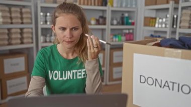 Yardım koordinatörü kadın, kalabalık bir merkez bağış etkinliğinde telefonla arıyor. Gönüllü olarak dizüstü bilgisayarında sarı tabelanın yanında raf kutusu kayıtları bulunuyor..