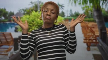 Kadın havuz inşaatında omuzlarını silker, avuçlarını kaldırır ve başını hafifçe eğer; belirsizlik..