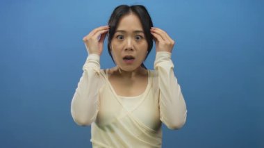 Krem rengi bluz giyen genç Çinli kadın şaşkınlığını dışa vuruyor..