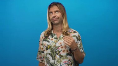 Stüdyoda göğsünde tropikal çiçekli gömlek ve omuzlarından dökülen uzun saçlı sarışın bir adam..