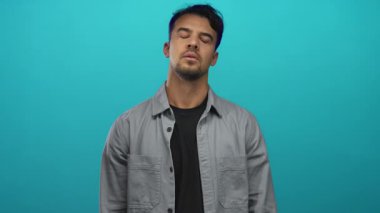 Genç İspanyol asıllı bir adam, izole edilmiş yeşil arka planda parmaklarıyla silah hareketi yapıyor. Ciddi bir ifade ve yoğun duygusal durum izlenimi veriyor.