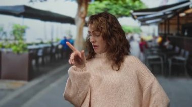 Parlak bir günde şehirdeki bir teras kafede oturan bir kadın kararlı ve sakin tavır sergiliyor..