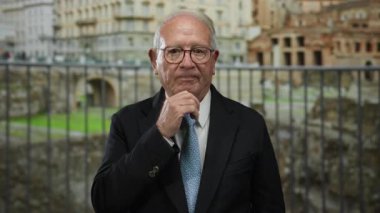 Takım elbiseli son sınıf öğrencisi, Roma harabelerinin önünde dikiliyor..