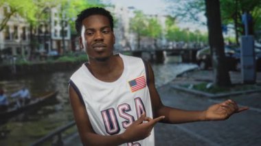 Beyaz ABD basketbol formalı adam dar kaldırım taşı caddesi boyunca kolunu uzatır; tefekkür ve güven.