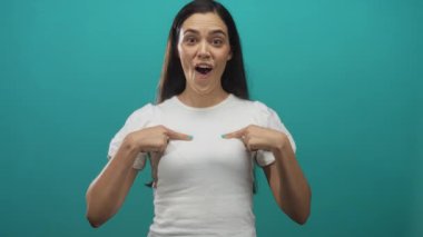 Genç İspanyol kadın stüdyoda parlak bir deniz mavisi zeminine karşı kameraya yumruk ve kiriş sallıyor; iyimserlik minnettarlığı.