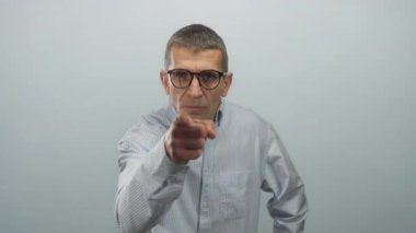 Gözlüklü, çizgili tişörtlü bir adam kameraya beyaz bir arka planda özgüvenli bir şekilde bakarken, bir anlık bir nişanlanma görüntüsü yakalıyor..