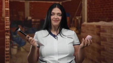 İnşaat alanında makyajdan hoşlanan bir kadın fırça ve süngerle iç mekanda beyaz üniforma giyiyor..