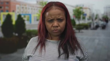 Afro-Amerikalı kadınlar, park halindeki arabalar ve saksı ağaçlarıyla dolu bir caddede parmakla işaret ediyorlar..