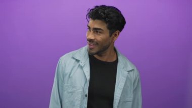 Küpeli ve parmağıyla stüdyoda gülümseyen genç İspanyol adam; mutluluk pozitifliği.