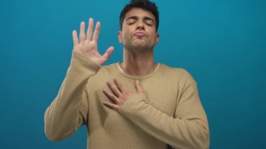 Adam arka plan çerçevesinde yemin etmek için elini kaldırırken İspanyol genç adam yemin etmeden önce mavi ışıkta ciddi bir poz veriyor..