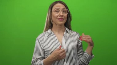 Stüdyo yeşil ekranında açık elleri olan, gözlüklü, gülümseyen sarışın kadın şaşırttı..