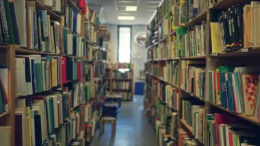 Kapalı bir kütüphane ortamındaki bulanık kitaplar renkli dikenler ve uzun kitaplıklarla bir bokeh etkisi yaratıyor, sessiz keşifleri ve çalışmayı davet ediyor..