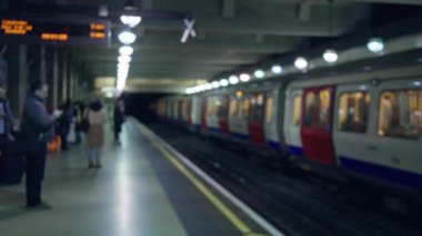 Londra yeraltı istasyonunda bekleyen bulanık yolcuların dikkati dağılmış trenin Bokeh ışıklandırması altında gelmesiyle.