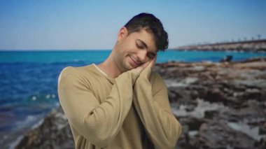 Adam elleri üzerinde, İspanyol sahil şeridinin yanındaki kumullarda dinlenirken açık havada uyuyan adam sakin bir parıltıyla deniz kenarına bakıyor..