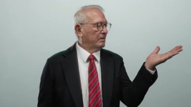 Takım elbiseli kıdemli adam beyaz arka planda el hareketleriyle izole edilmiş bir konsept sergiliyor..