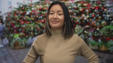 Genç bir kadın gülümsüyor ve açık bir şehir sokağında canlı çiçeklerle barış işareti yapıyor, neşeli şehir deneyimini yakalıyor..