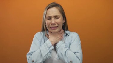 Turuncu arka planda boğulan bir kadın boğazında ağrı ve sıkıntı gösteriyor. Sağlık sorununu ve solunum sorununu vurguluyor..